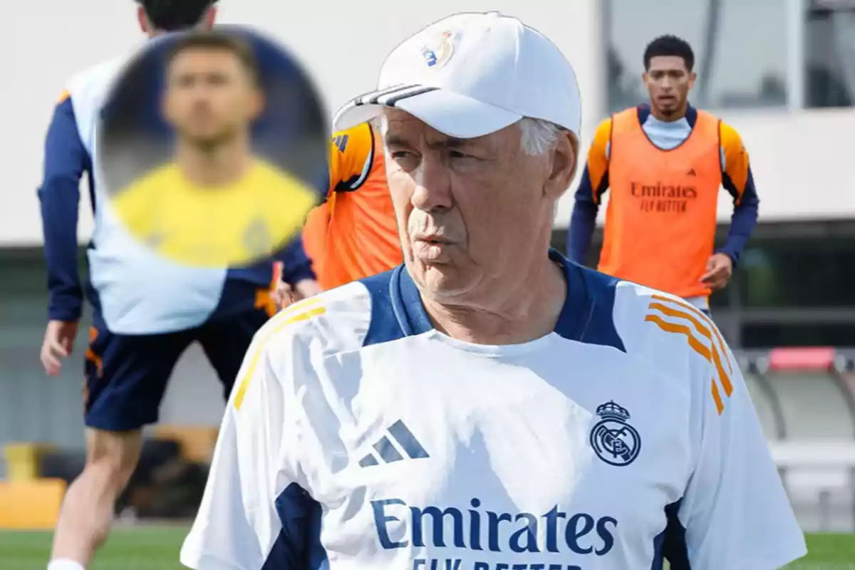 Un entrenador de fútbol del Real Madrid en un campo de entrenamiento con jugadores al fondo.