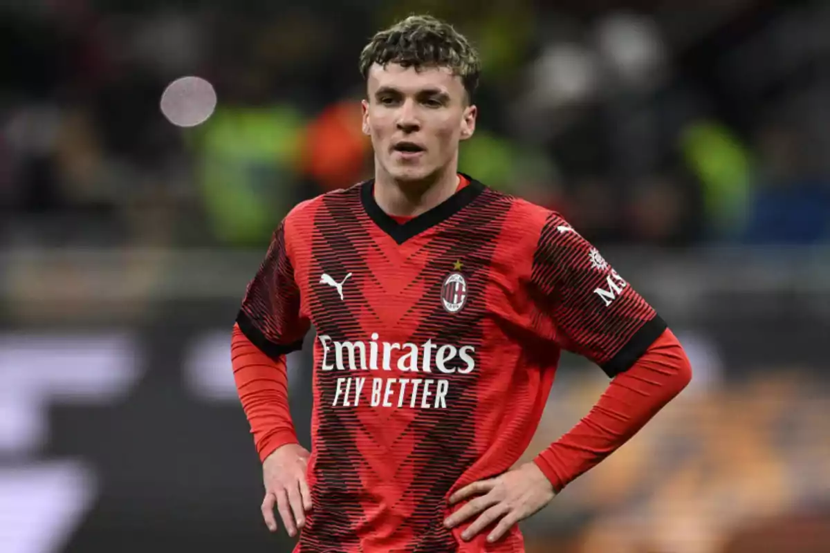 Un jugador de fútbol con el uniforme rojo y negro del AC Milan en el campo de juego.