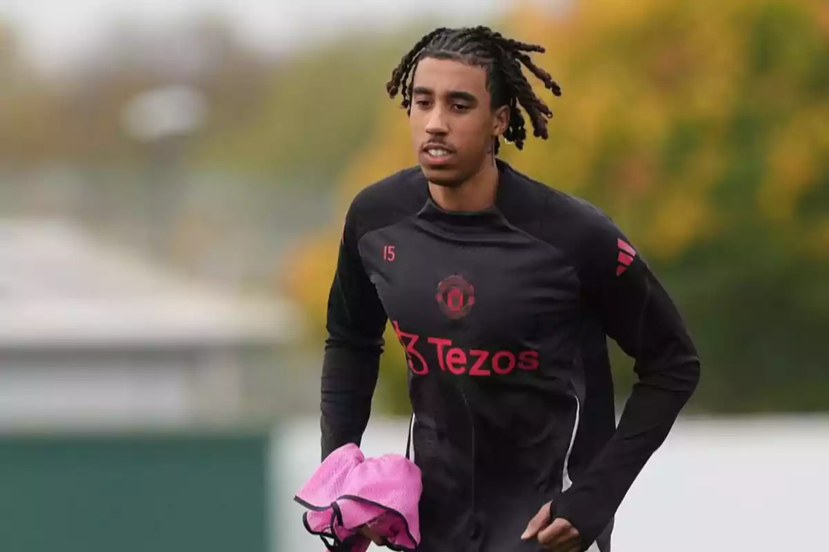 A player in a black training uniform with pink details runs on a field. A player in a black training uniform with pink details runs on a field.