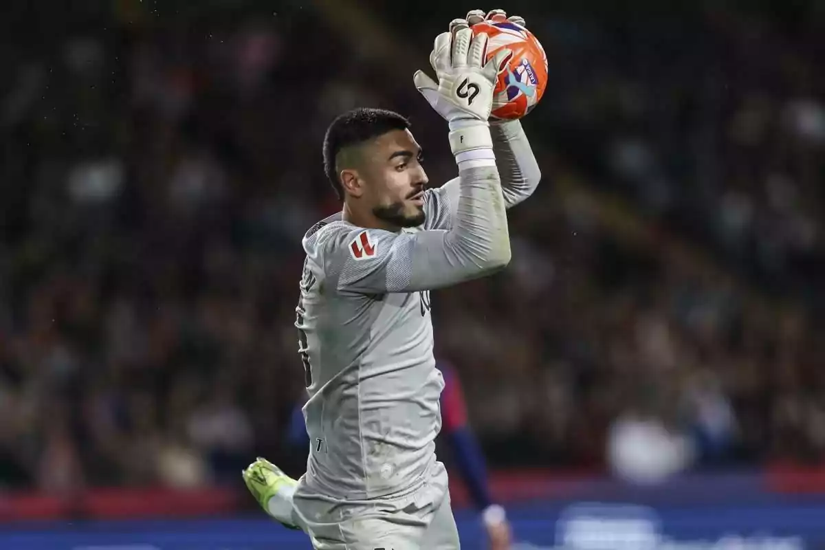 Un portero de fútbol atrapa el balón con ambas manos durante un partido. Un portero de fútbol atrapa el balón con ambas manos durante un partido.
