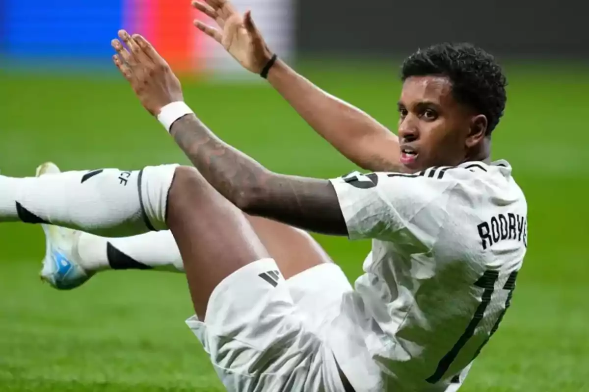 Jugador de fútbol con uniforme blanco cayendo al suelo durante un partido. Jugador de fútbol con uniforme blanco cayendo al suelo durante un partido.