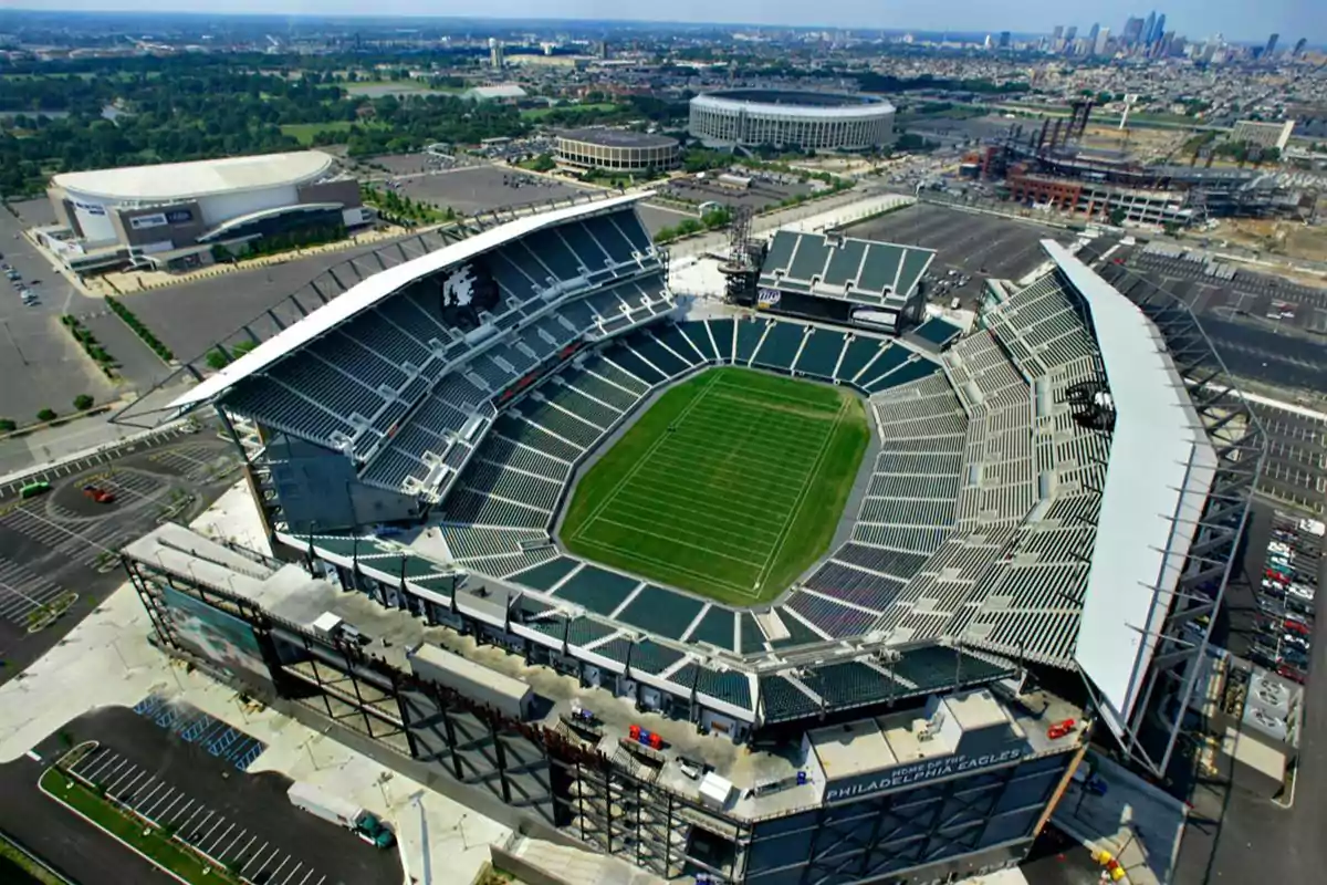Aerial view of an empty football stadium surrounded by parking lots and buildings in a city Aerial view of an empty football stadium surrounded by parking lots and buildings in a city