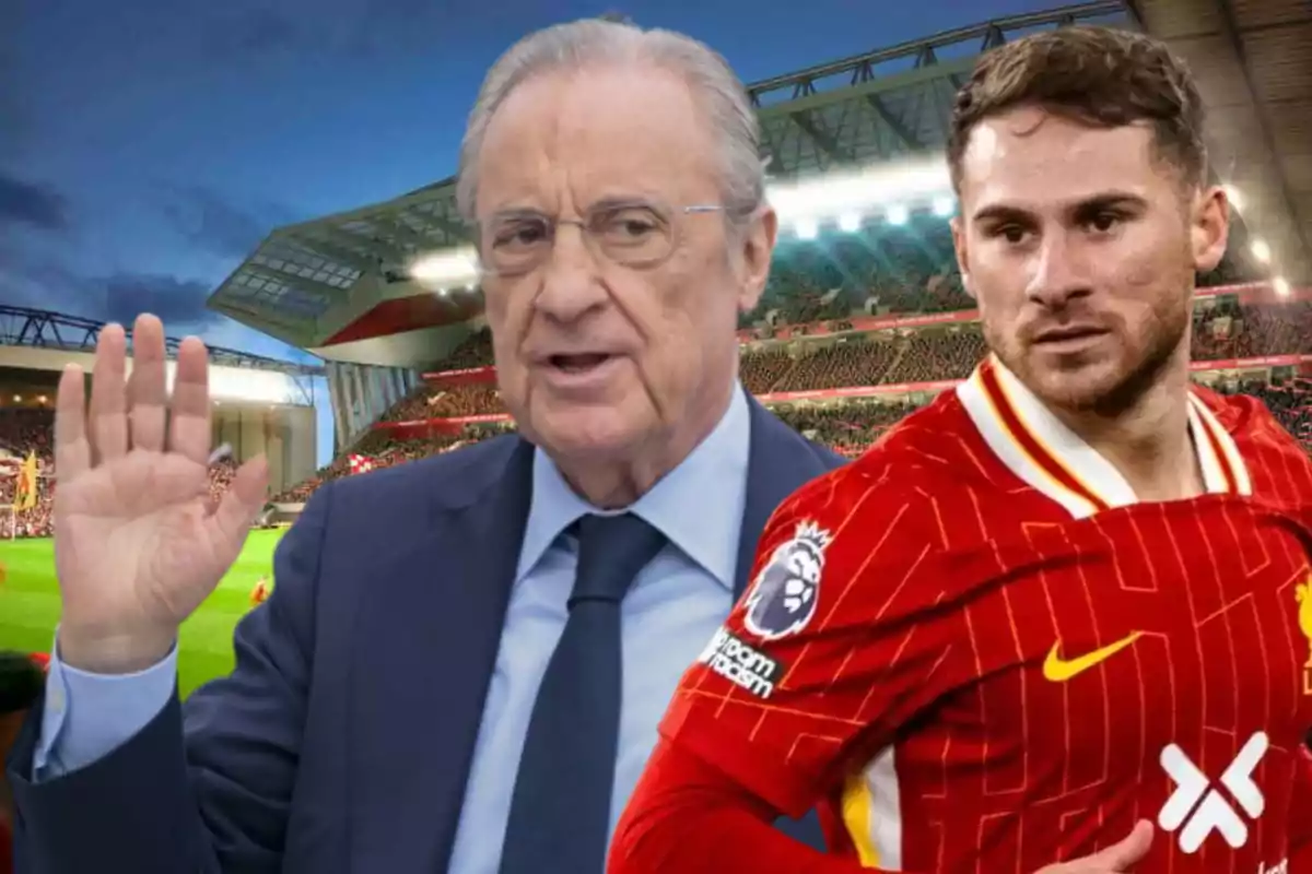 An older man in a suit and glasses raises his hand while a player in a red uniform stands next to him in a lit-up stadium.
