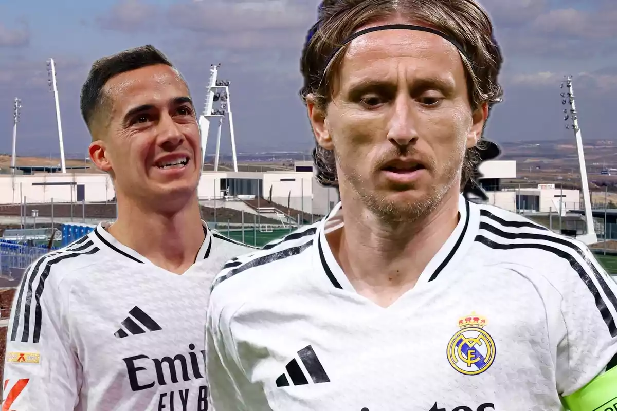 Two players in white Real Madrid uniforms pose in front of a training field with lighting structures in the background.