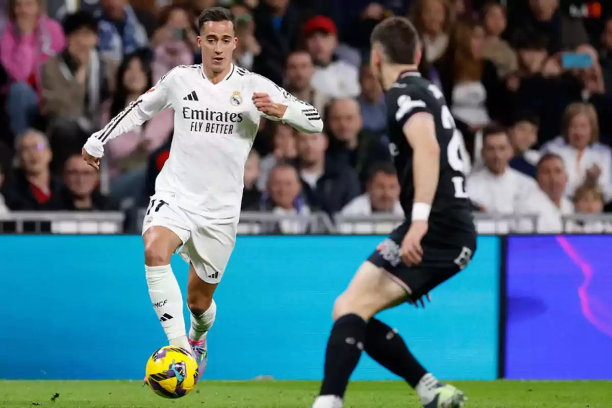 Jugador de fútbol del Real Madrid en acción durante un partido, con un oponente cerca y el público de fondo. Jugador de fútbol del Real Madrid en acción durante un partido, con un oponente cerca y el público de fondo.