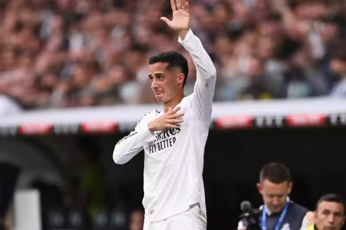 A player in a white uniform raises his hand and touches his chest in a stadium full of spectators. A player in a white uniform raises his hand and touches his chest in a stadium full of spectators.
