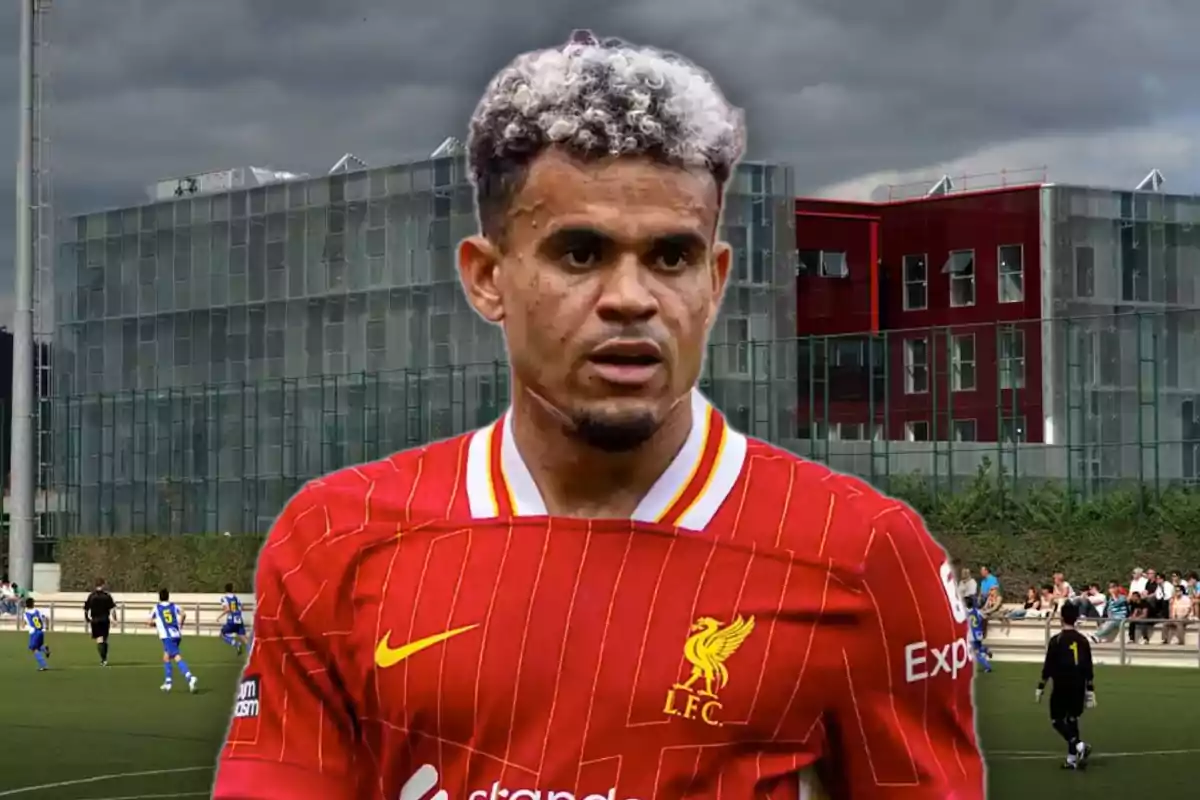 Futbolista con uniforme rojo del Liverpool en primer plano con un edificio moderno y un campo de fútbol al fondo