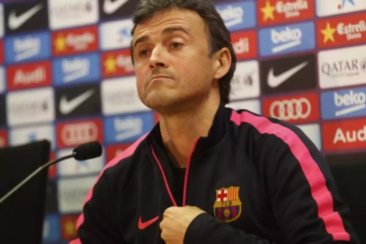 FC Barcelona coach at a press conference with a sponsor backdrop and a microphone in front of him FC Barcelona coach at a press conference with a sponsor backdrop and a microphone in front of him