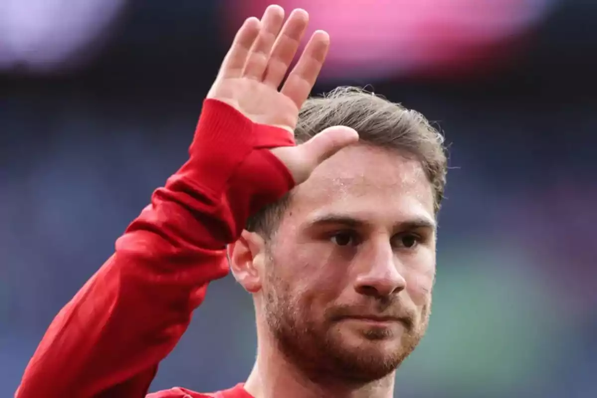 A man in a red jersey raising his hand in greeting. A man in a red jersey raising his hand in greeting.