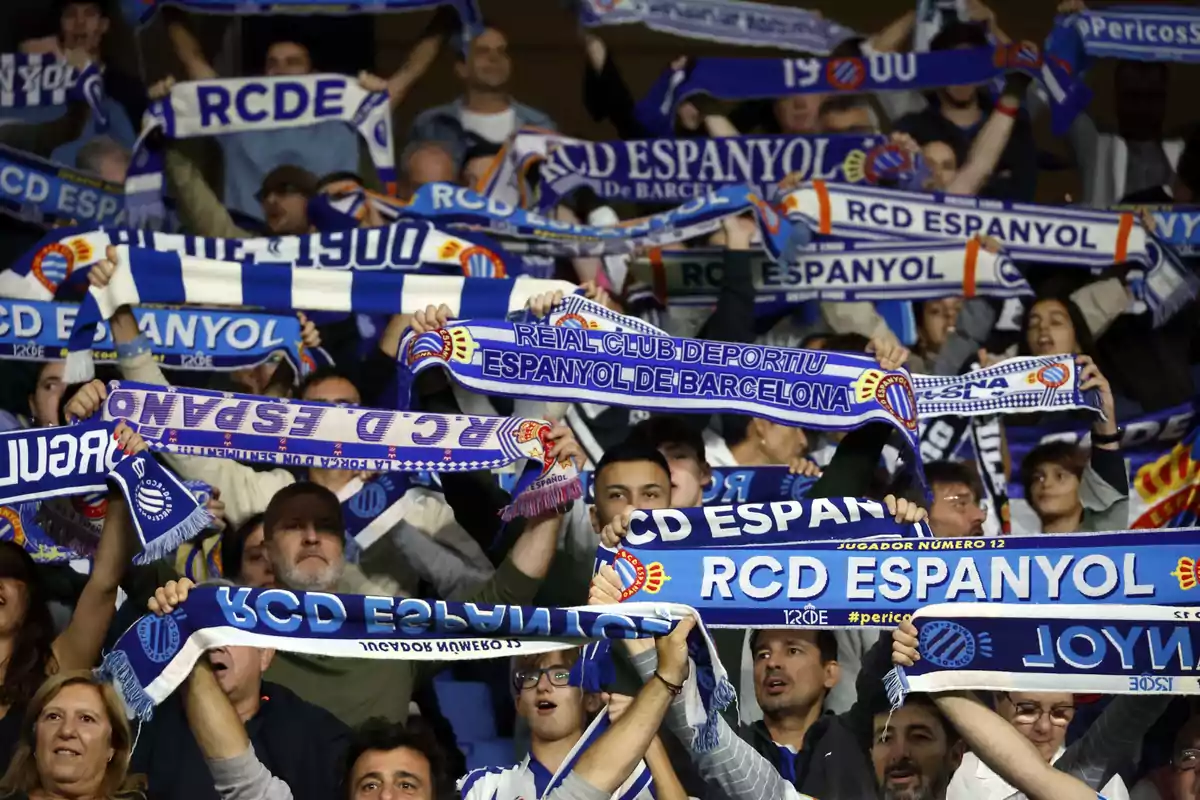 RCD Espanyol fans holding team scarves at a stadium.