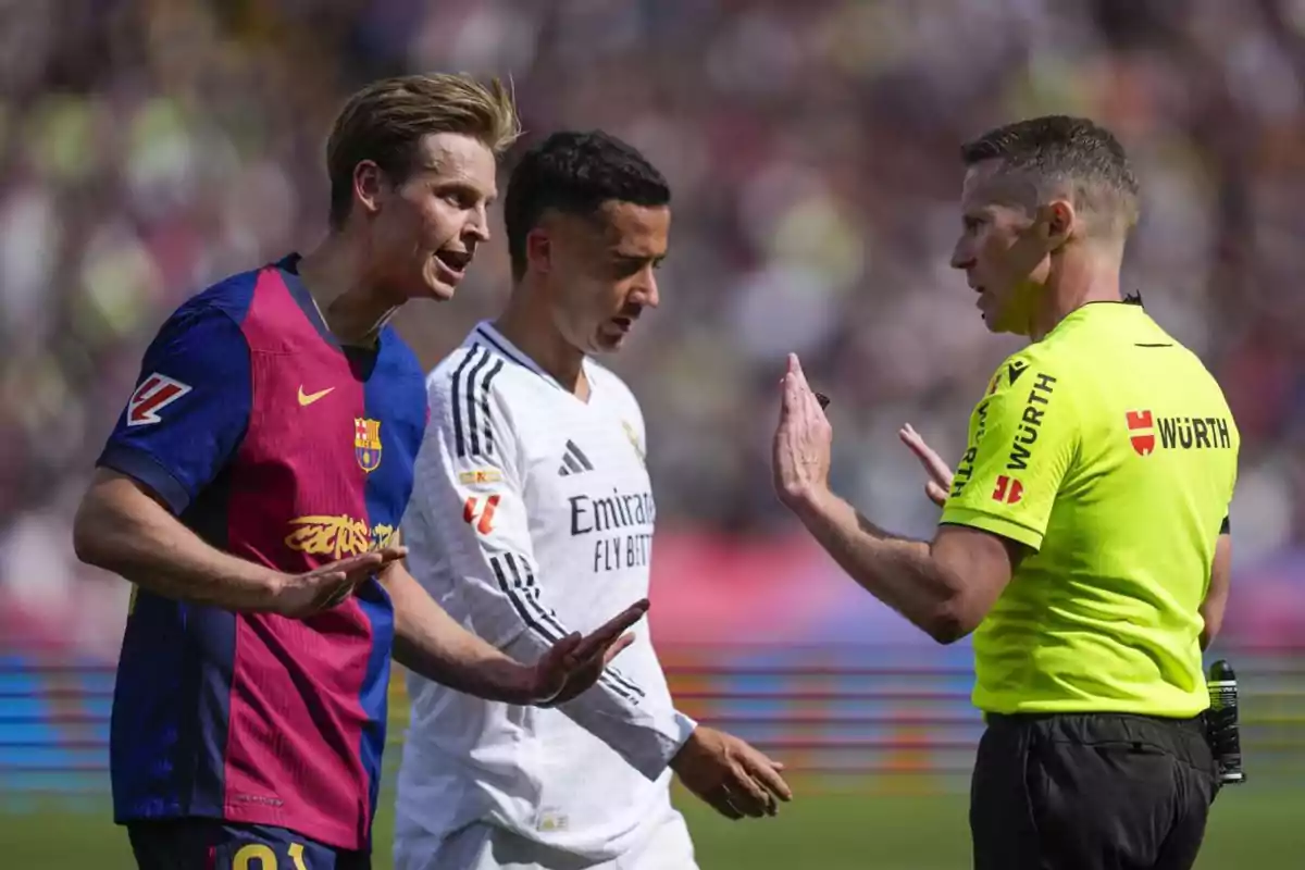 Un jugador de fútbol discute con el árbitro mientras otro jugador observa durante un partido. Un jugador de fútbol discute con el árbitro mientras otro jugador observa durante un partido.
