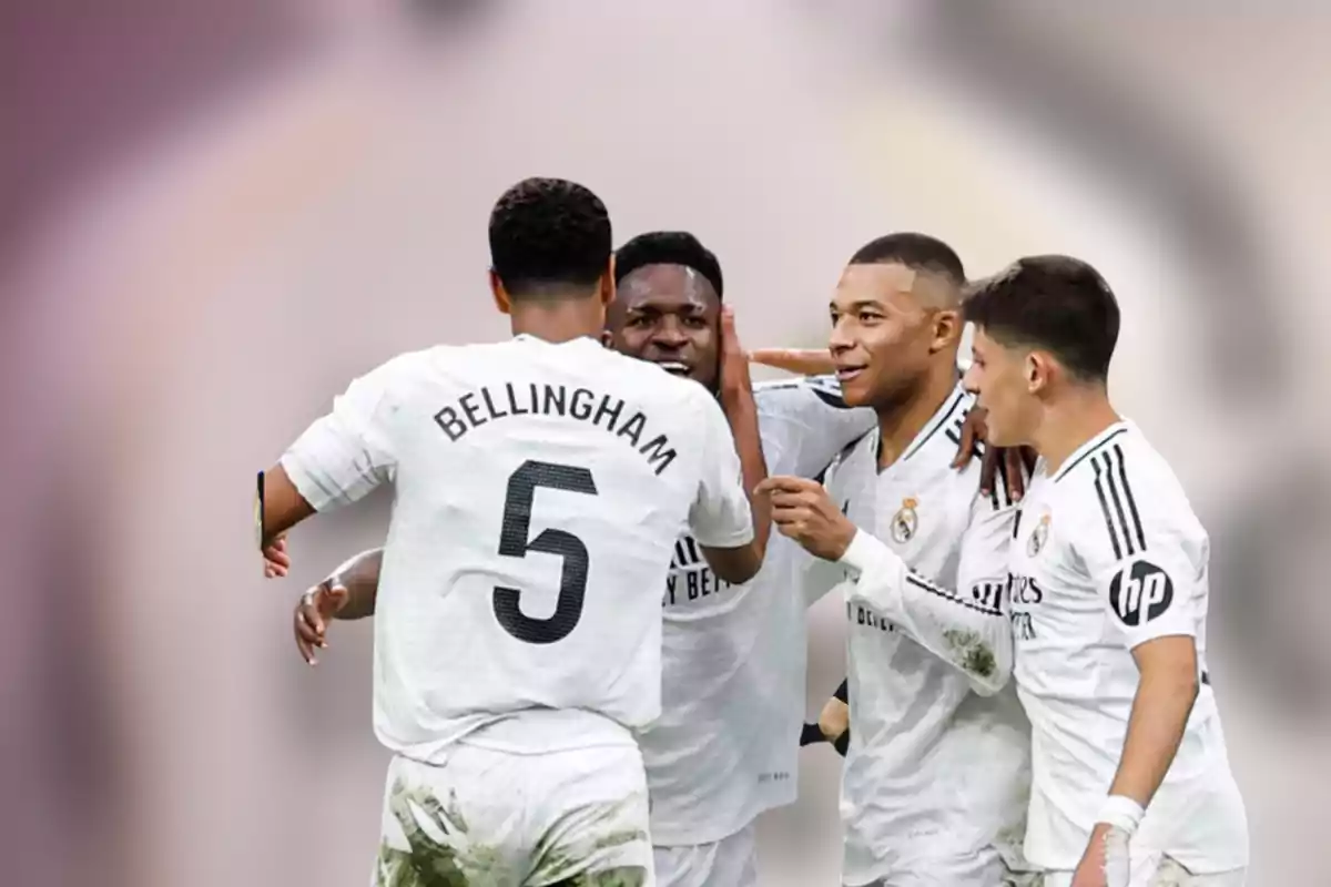 Four Real Madrid players celebrate together on the field in white uniforms.
