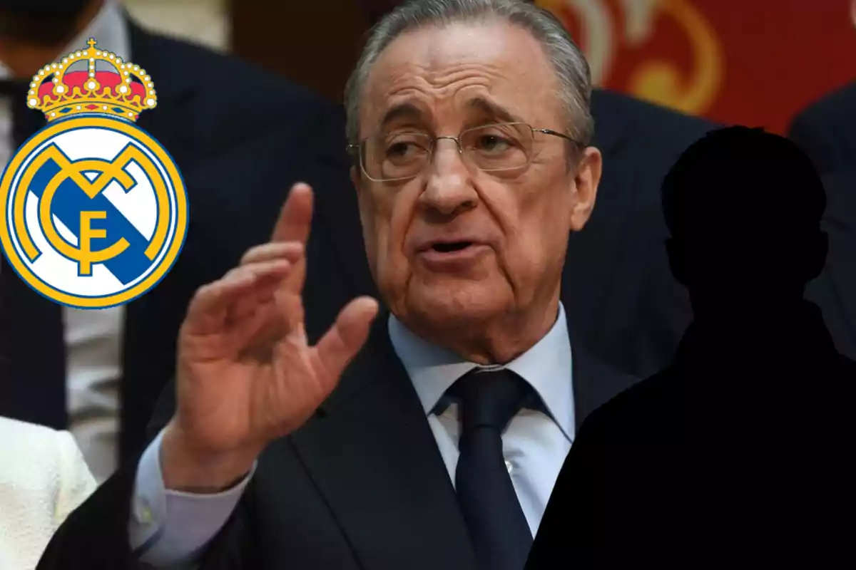 Older man with glasses and a suit speaking, next to the Real Madrid crest and the black silhouette of a person beside him