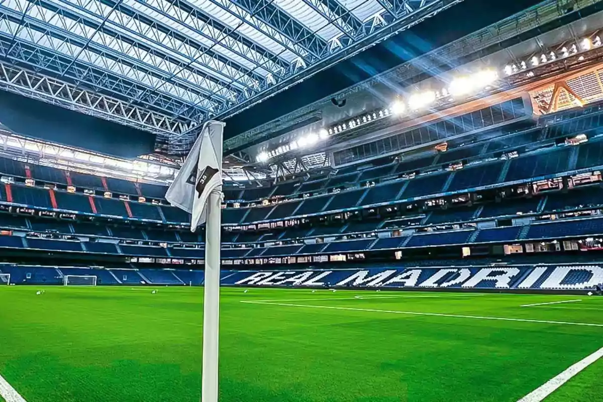 Estadio de fútbol con césped verde y gradas vacías iluminadas por luces artificiales.