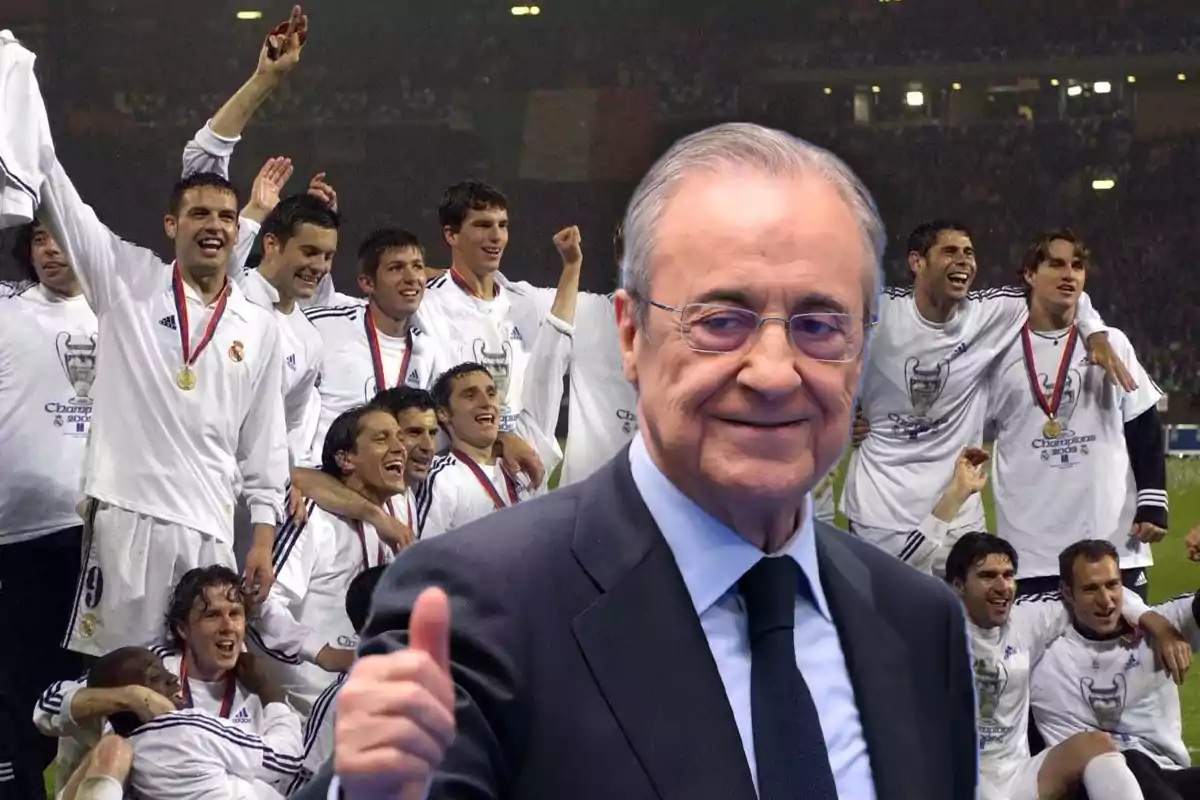 A man in a suit smiles and gives a thumbs up in front of a group of players celebrating with medals and white jerseys in a stadium full of spectators.