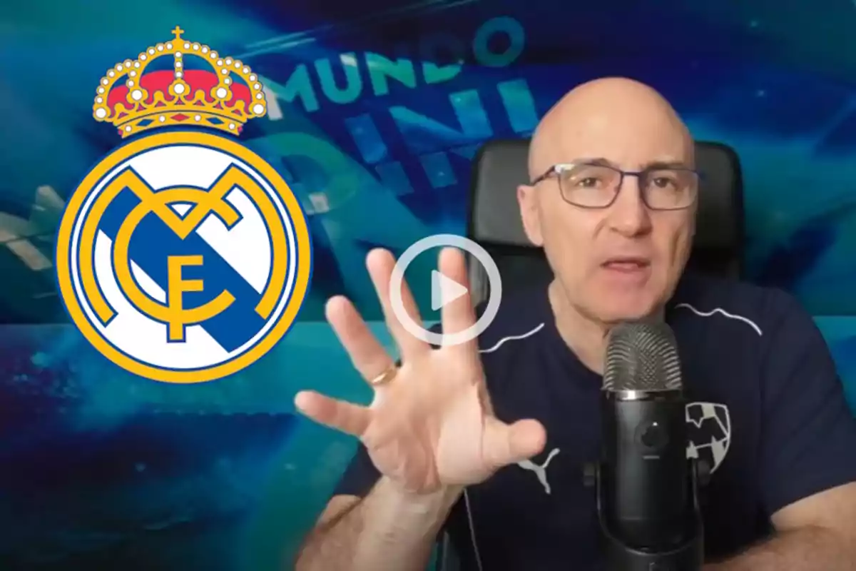 A man with glasses and a sports jersey speaks in front of a microphone with the Real Madrid logo next to him.