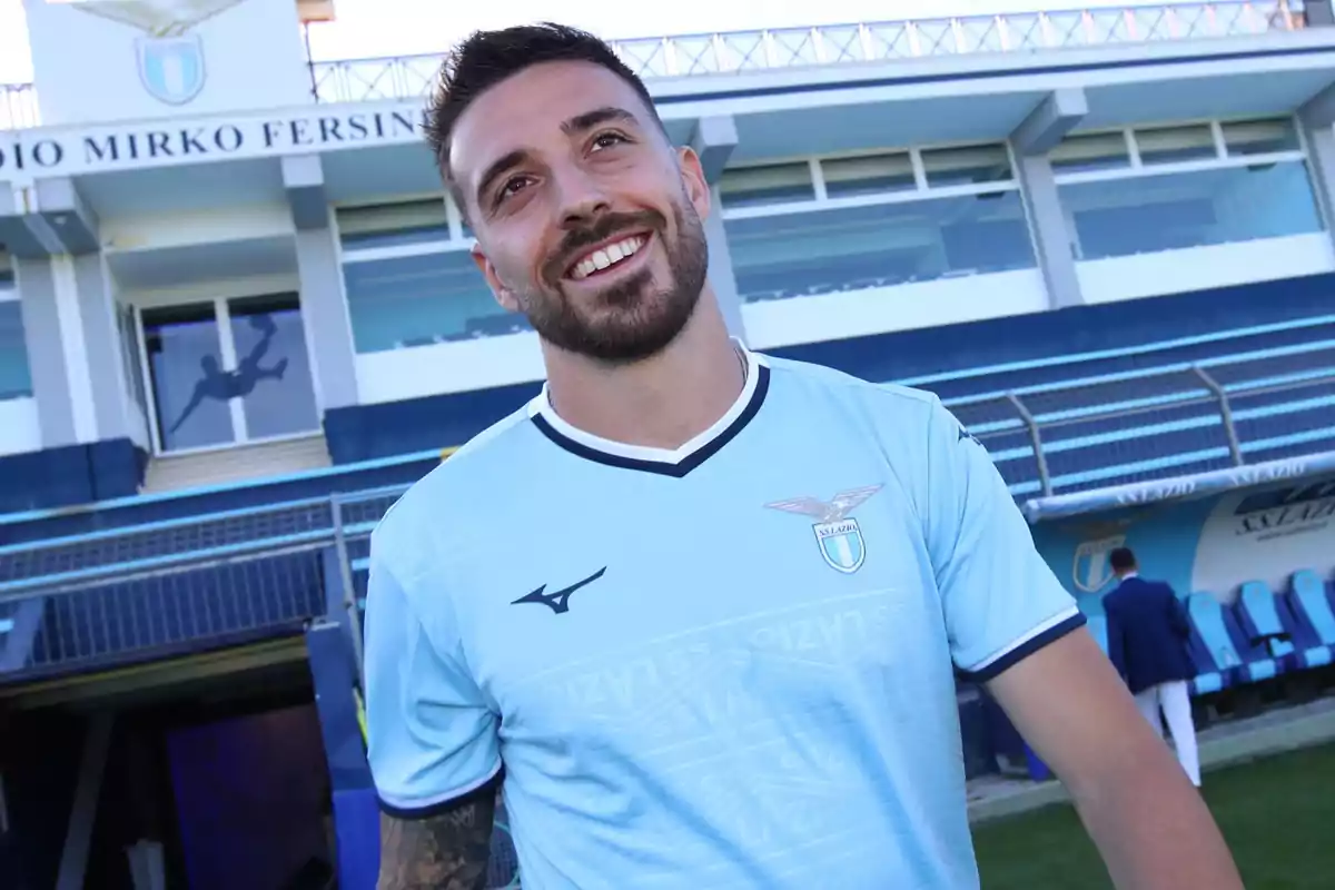 Soccer player wearing Lazio’s light blue jersey smiling in front of a stadium Soccer player wearing Lazio’s light blue jersey smiling in front of a stadium
