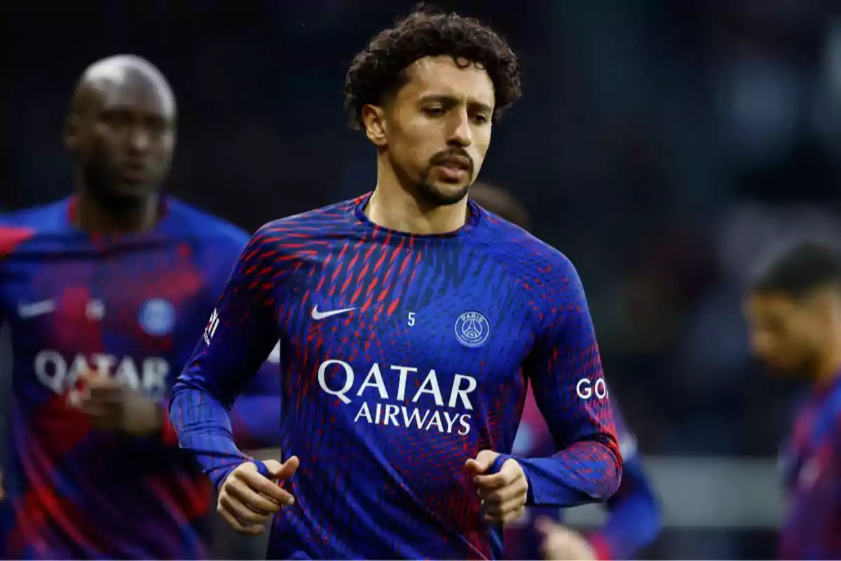A player in a blue and red PSG uniform runs on the field during a match. A player in a blue and red PSG uniform runs on the field during a match.