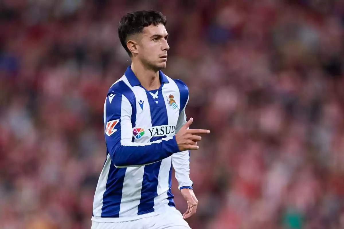 Soccer player wearing a Real Sociedad uniform on the field during a match Soccer player wearing a Real Sociedad uniform on the field during a match