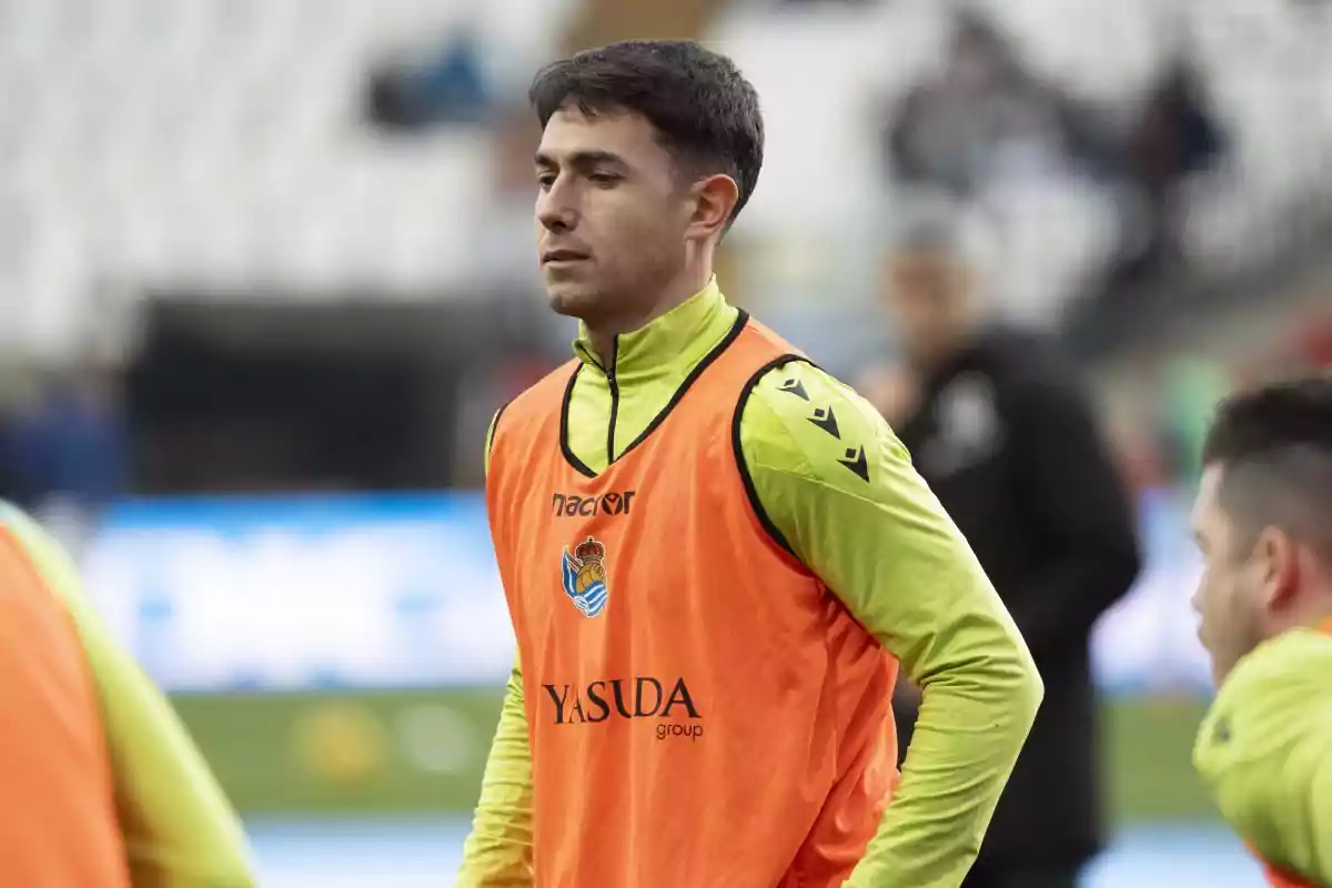 Soccer player wearing an orange training vest on a field before a match Soccer player wearing an orange training vest on a field before a match