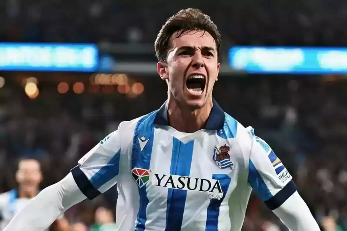 Un jugador de fútbol celebrando con entusiasmo mientras lleva el uniforme de la Real Sociedad. Un jugador de fútbol celebrando con entusiasmo mientras lleva el uniforme de la Real Sociedad.