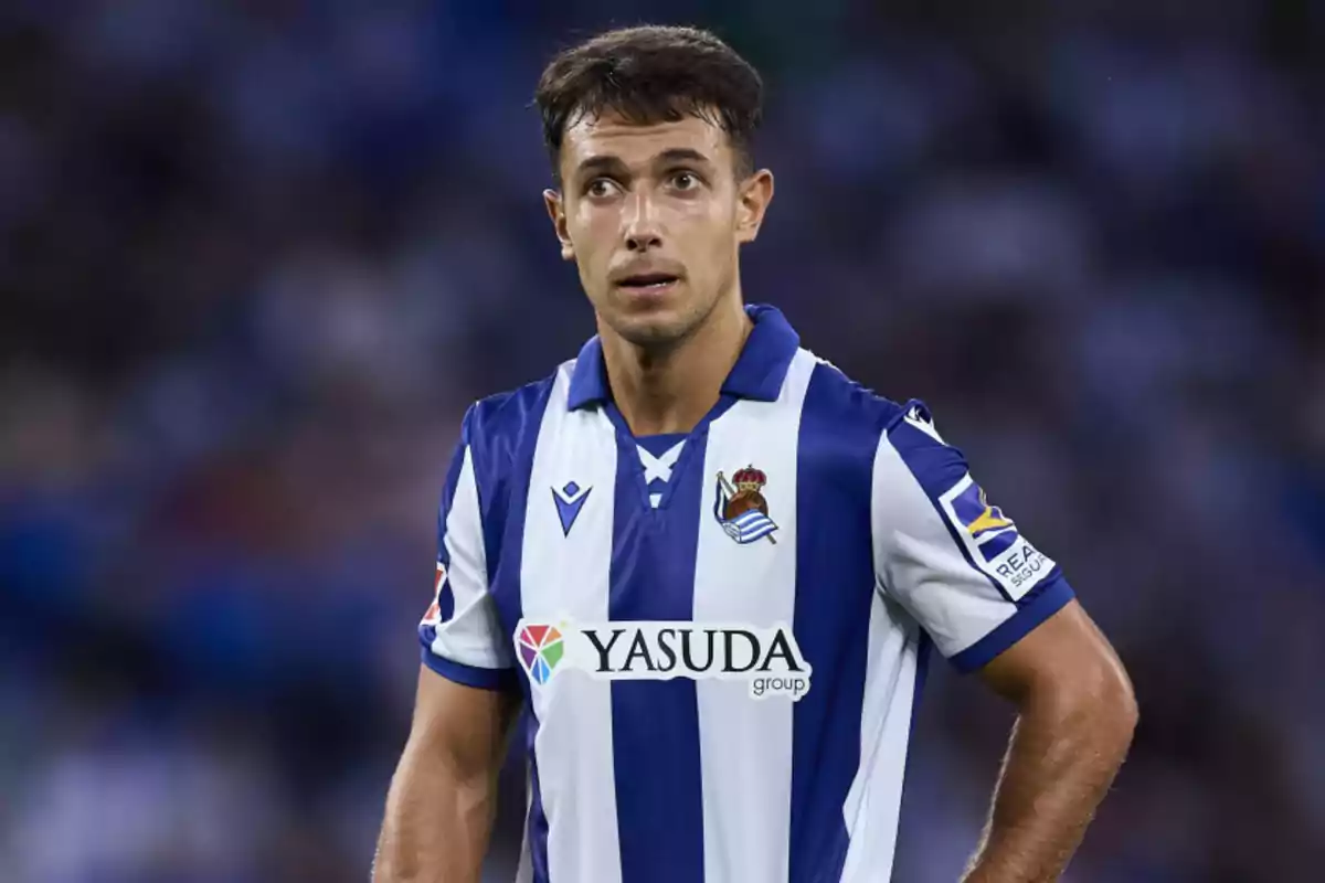 Jugador de fútbol con uniforme azul y blanco en el campo.