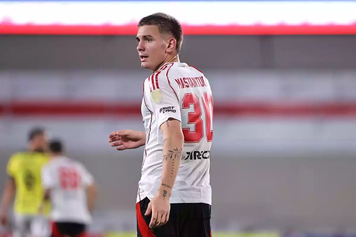 Soccer player in a white and red uniform on the field, displaying the number 30 and several tattoos on his arm Soccer player in a white and red uniform on the field, displaying the number 30 and several tattoos on his arm