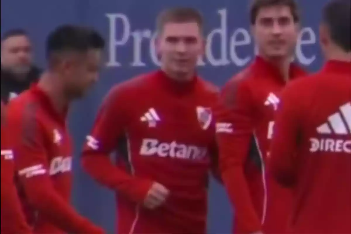Jugadores de fútbol con uniforme rojo entrenando en grupo