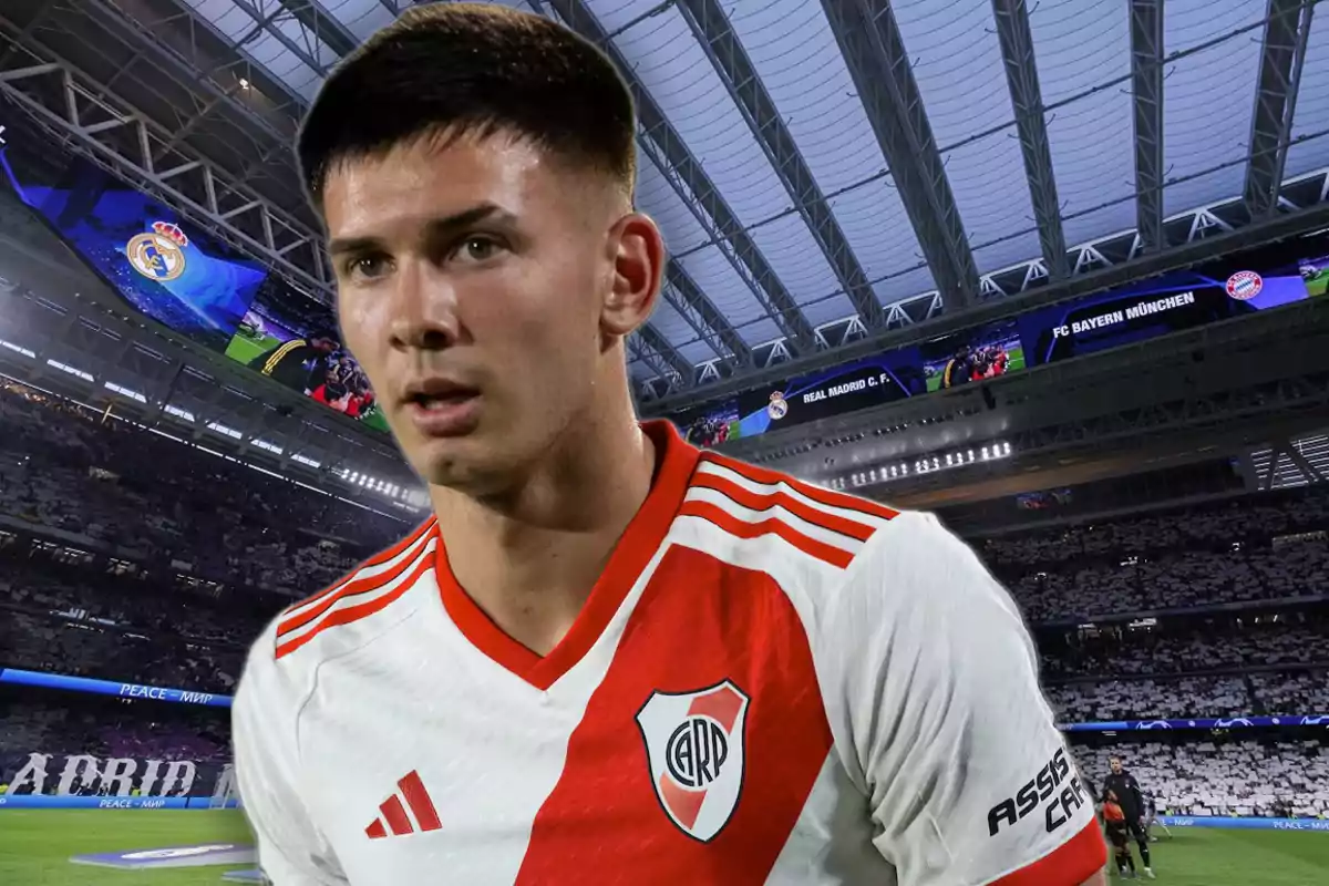 A player wearing the River Plate jersey is in a stadium with a covered roof and screens displaying the crests of Real Madrid and Bayern Munich.