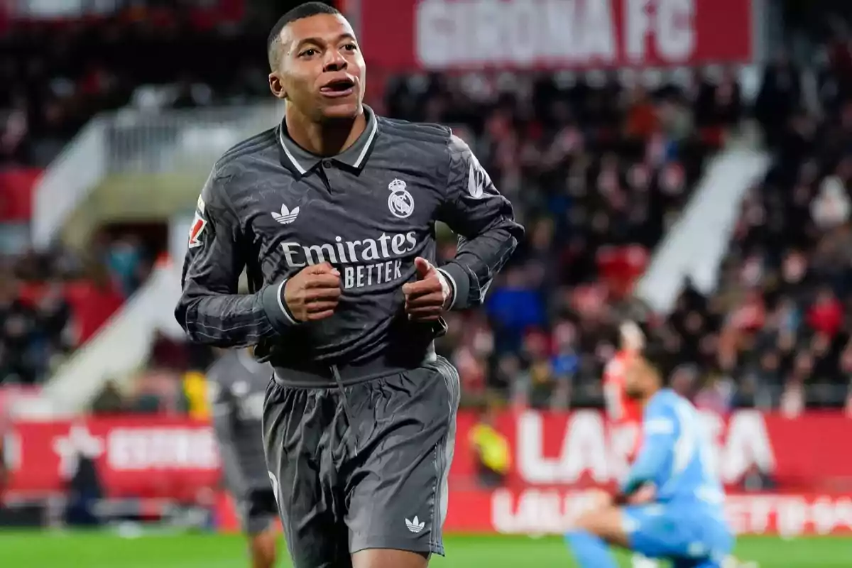 A soccer player in a gray uniform runs in a stadium during a match.