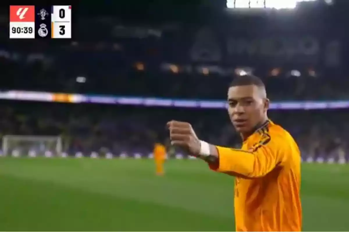 Un jugador de fútbol con uniforme naranja celebra en el campo mientras el marcador muestra 0 a 3 a favor del equipo visitante.