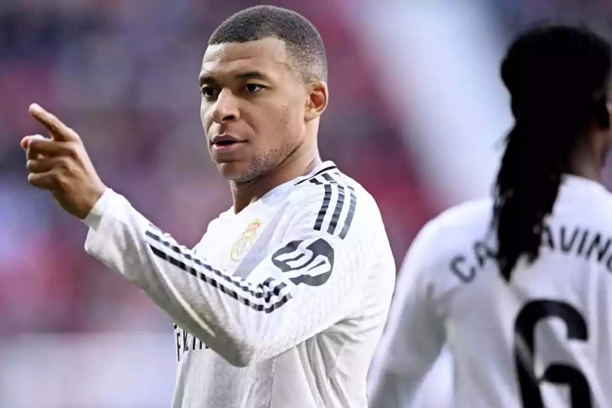 Un jugador de fútbol con uniforme blanco señala hacia adelante durante un partido.