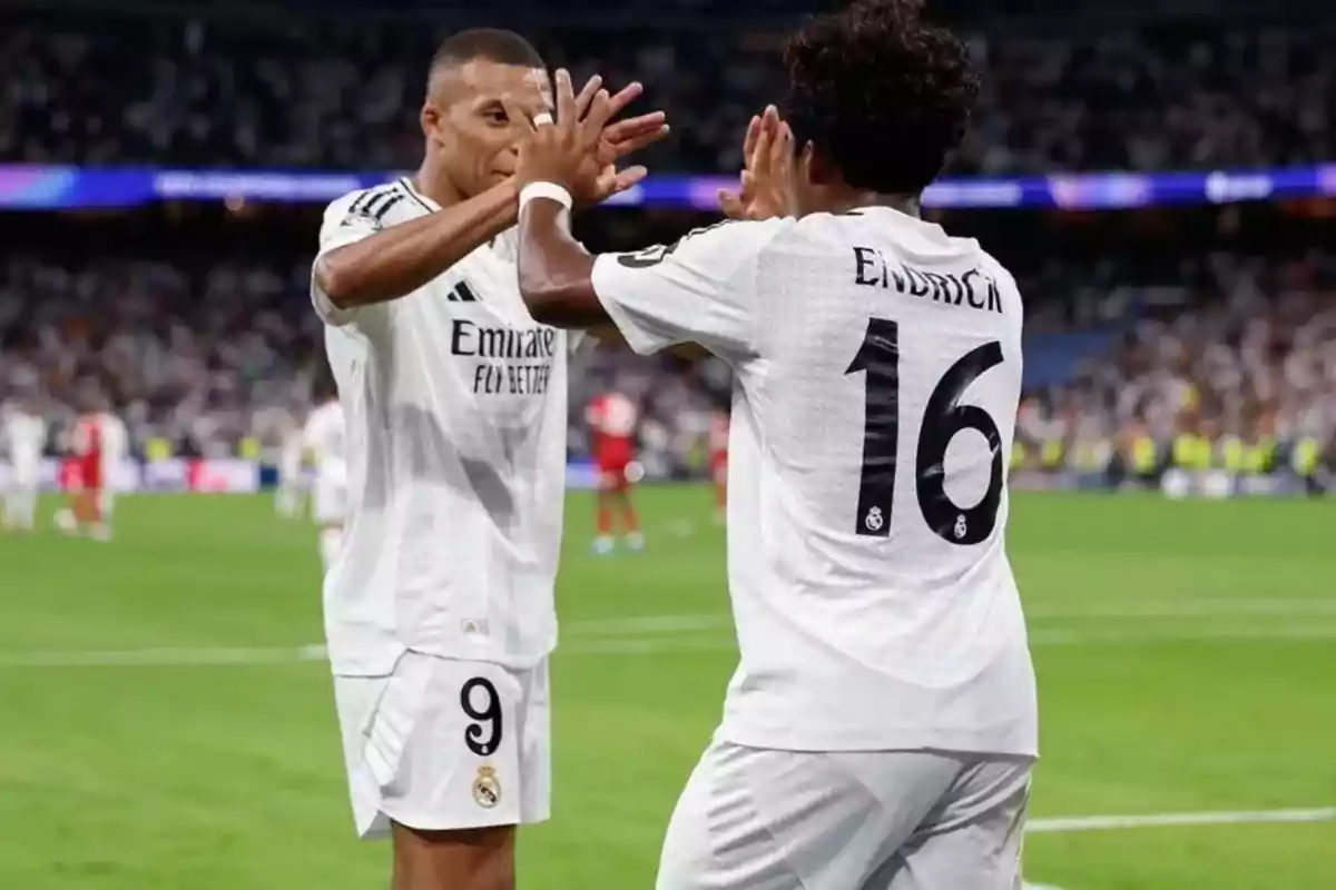 Two players from Real Madrid celebrate on the field by high-fiving. Two players from Real Madrid celebrate on the field by high-fiving.
