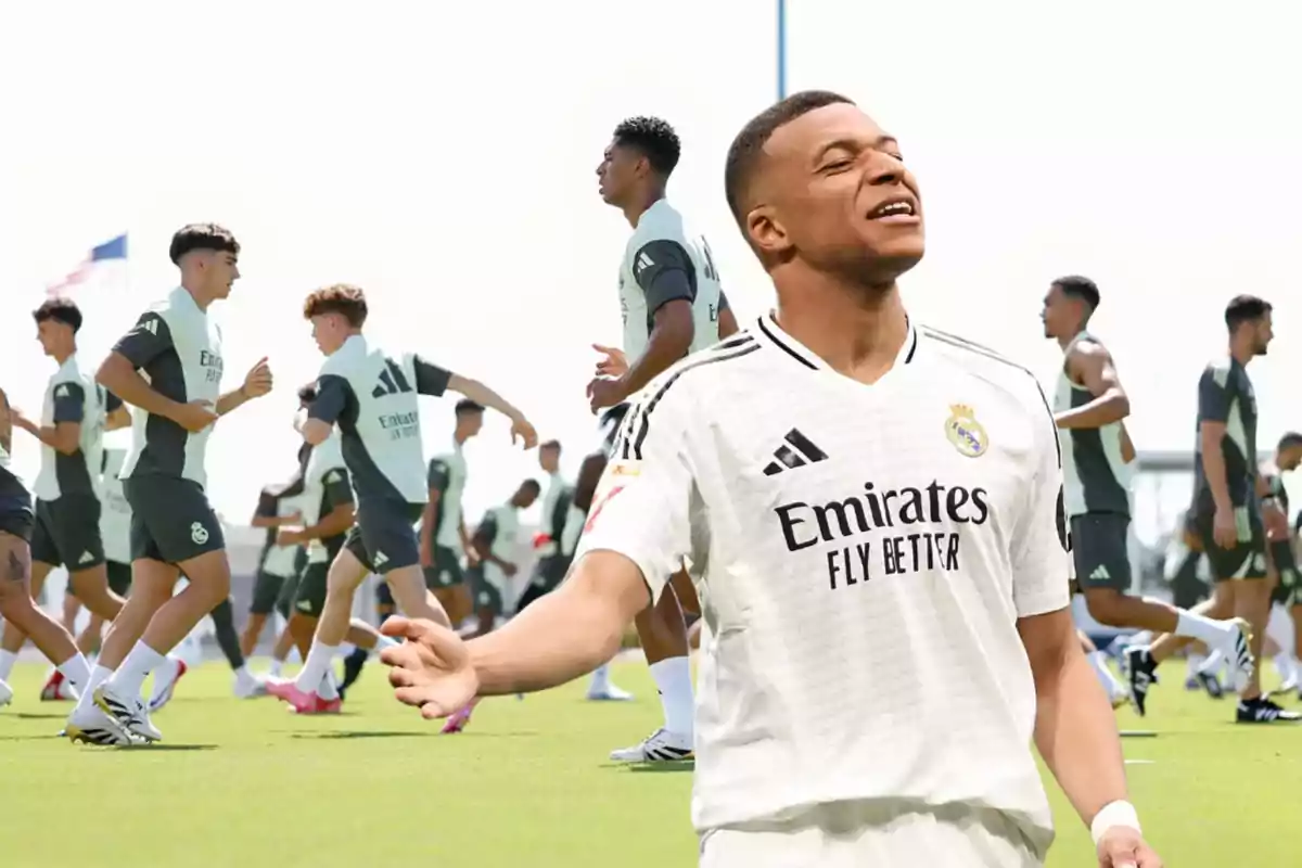 Futbolista con uniforme del Real Madrid en primer plano y jugadores entrenando en el campo al fondo