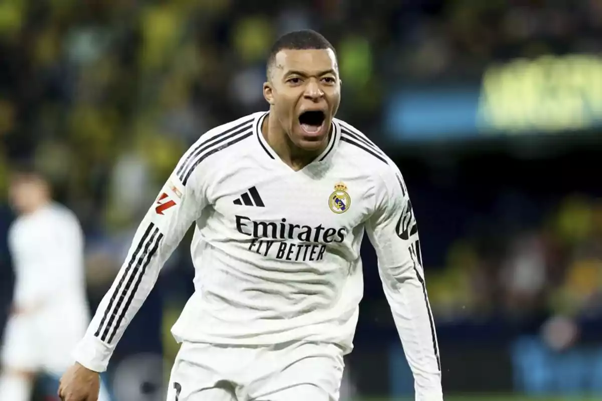Un jugador de fútbol con uniforme blanco celebra en el campo.