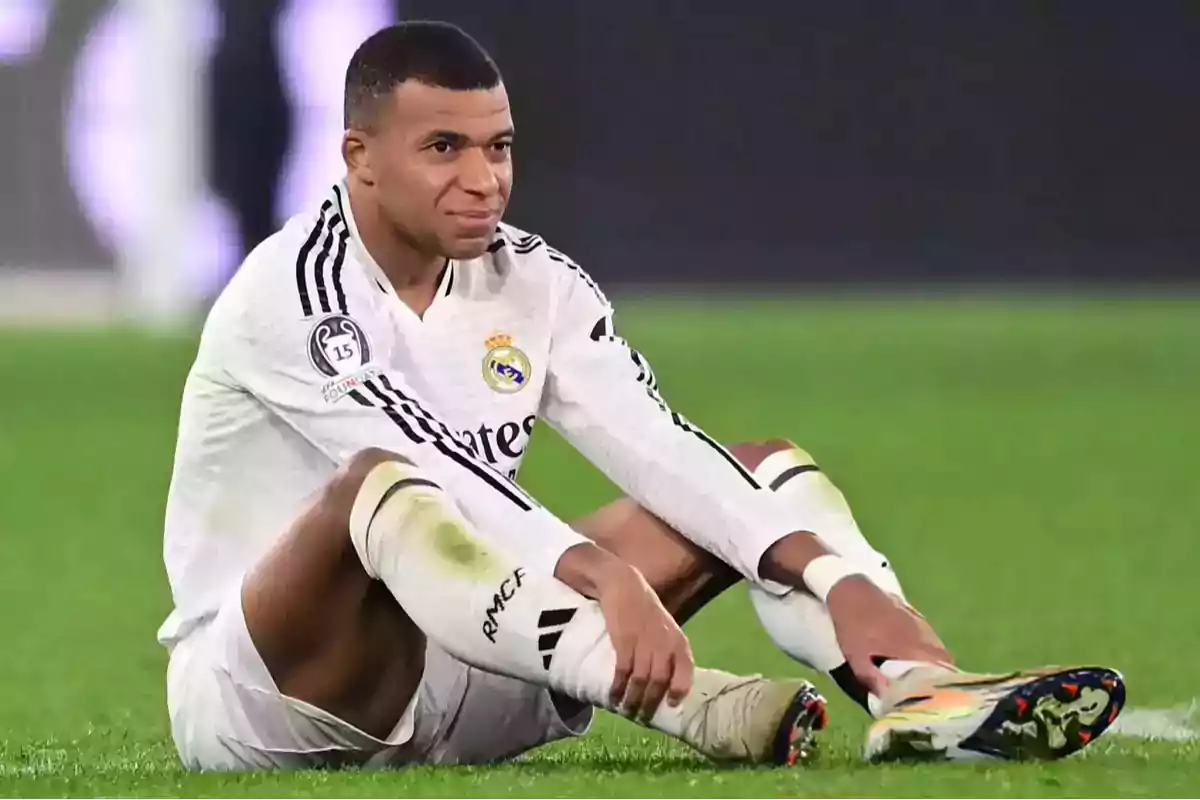 A soccer player in a white uniform is sitting on the playing field. A soccer player in a white uniform is sitting on the playing field.