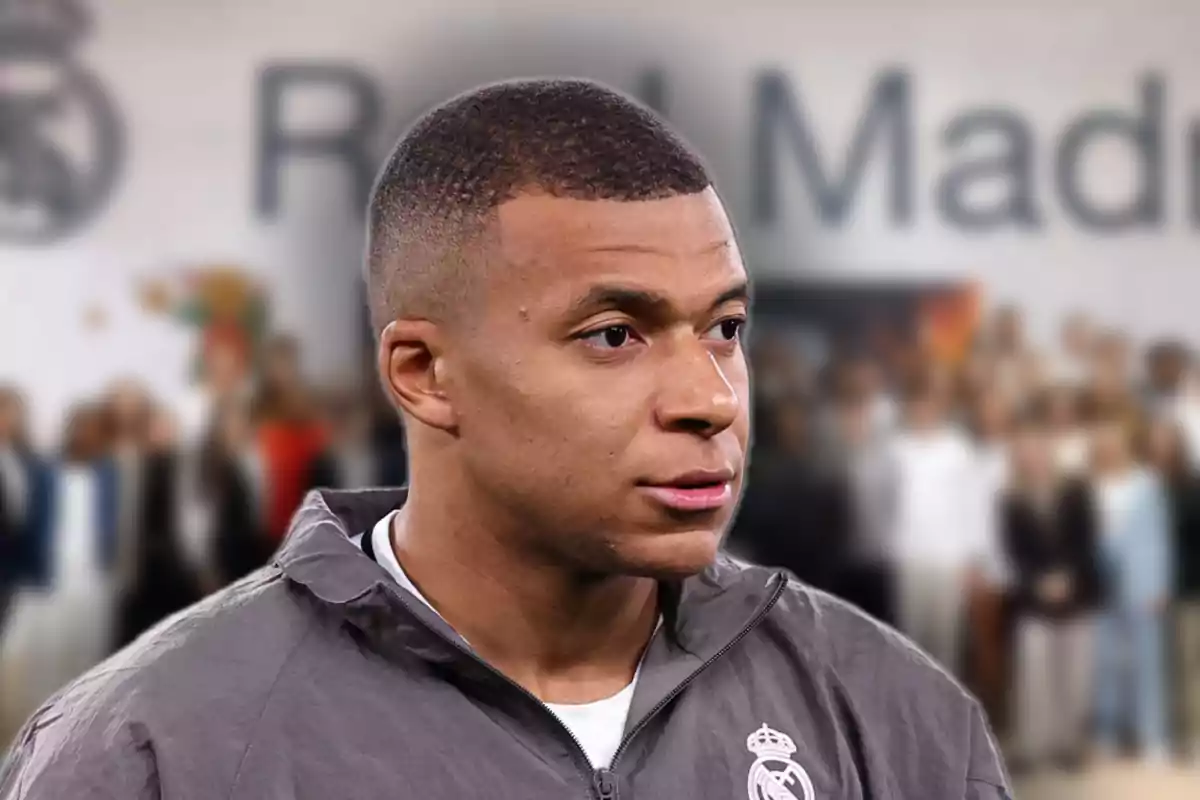 A soccer player wearing a Real Madrid jacket in a blurred background.