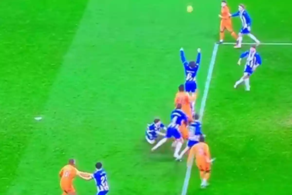 Soccer players in action during a match, with some wearing blue uniforms and others orange, while the ball is in the air.