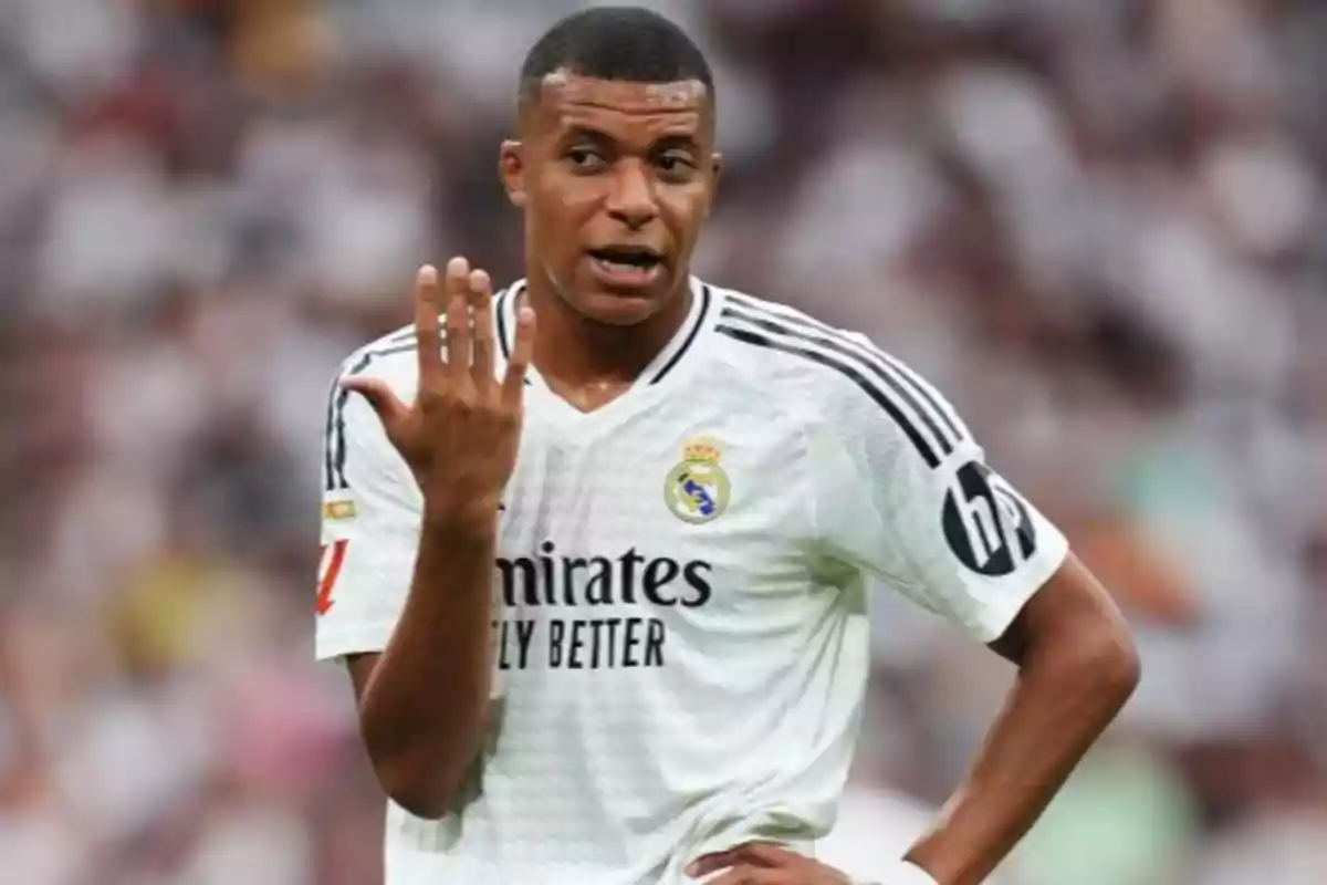 Un jugador de fútbol con uniforme blanco gesticula con la mano durante un partido.