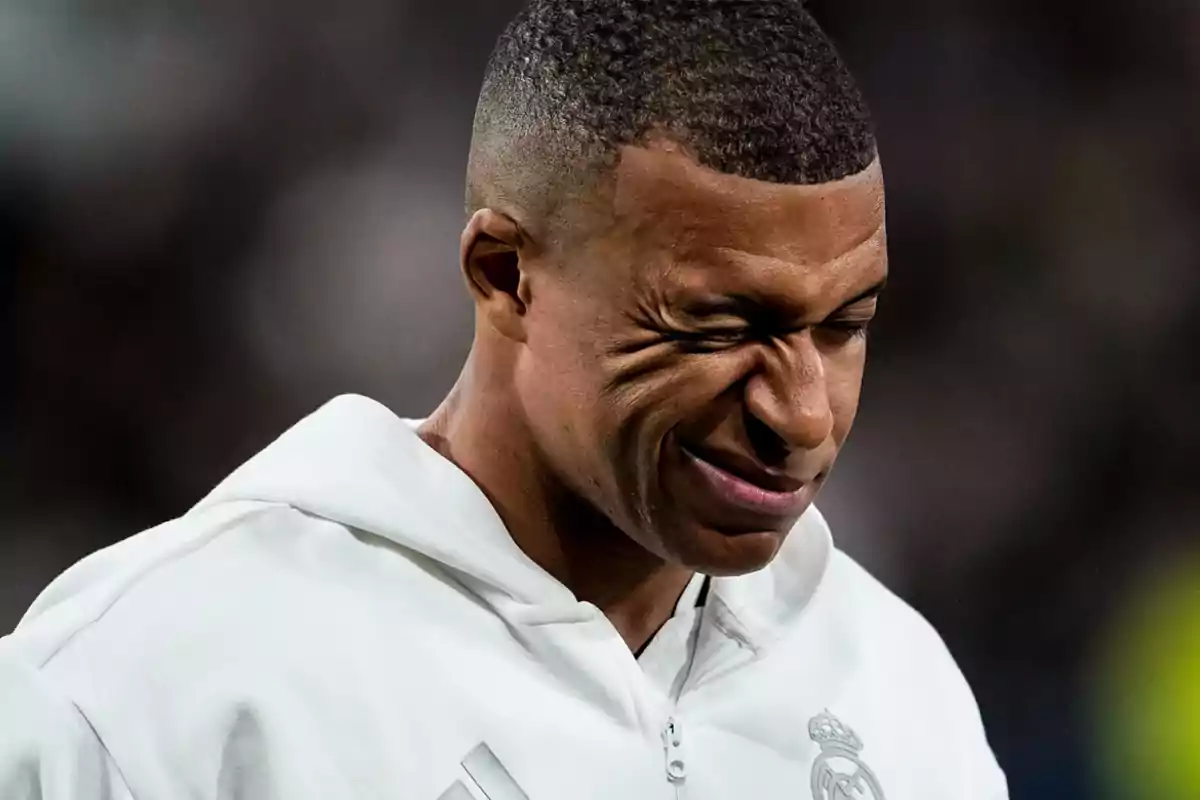 A man with a look of effort or concentration wearing a white sweatjersey.