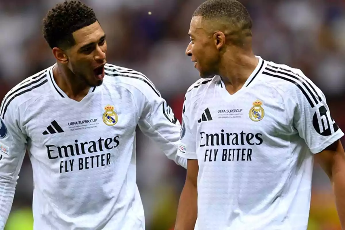 Two soccer players wearing white Real Madrid jerseys celebrate on the field. Two soccer players wearing white Real Madrid jerseys celebrate on the field.