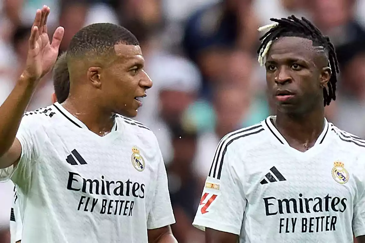 Two Real Madrid soccer players chatting on the field during a match.