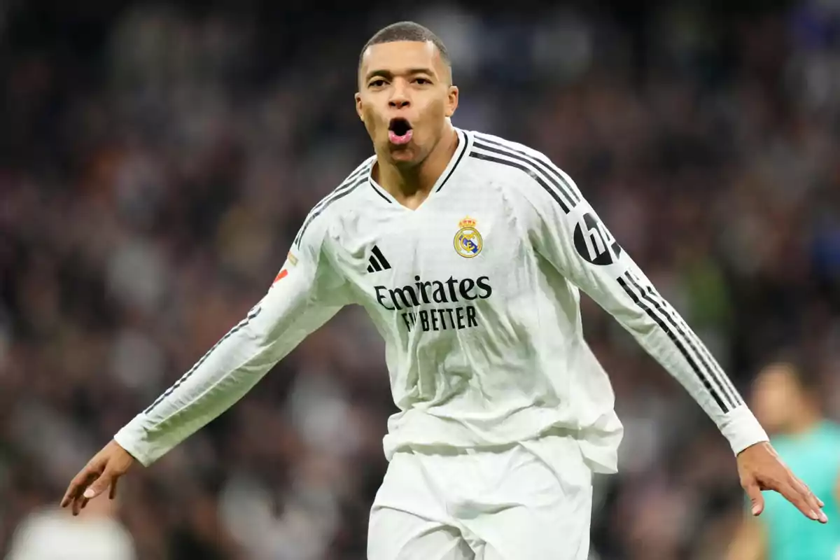 Un jugador de fútbol celebrando un gol con la camiseta blanca de un equipo.