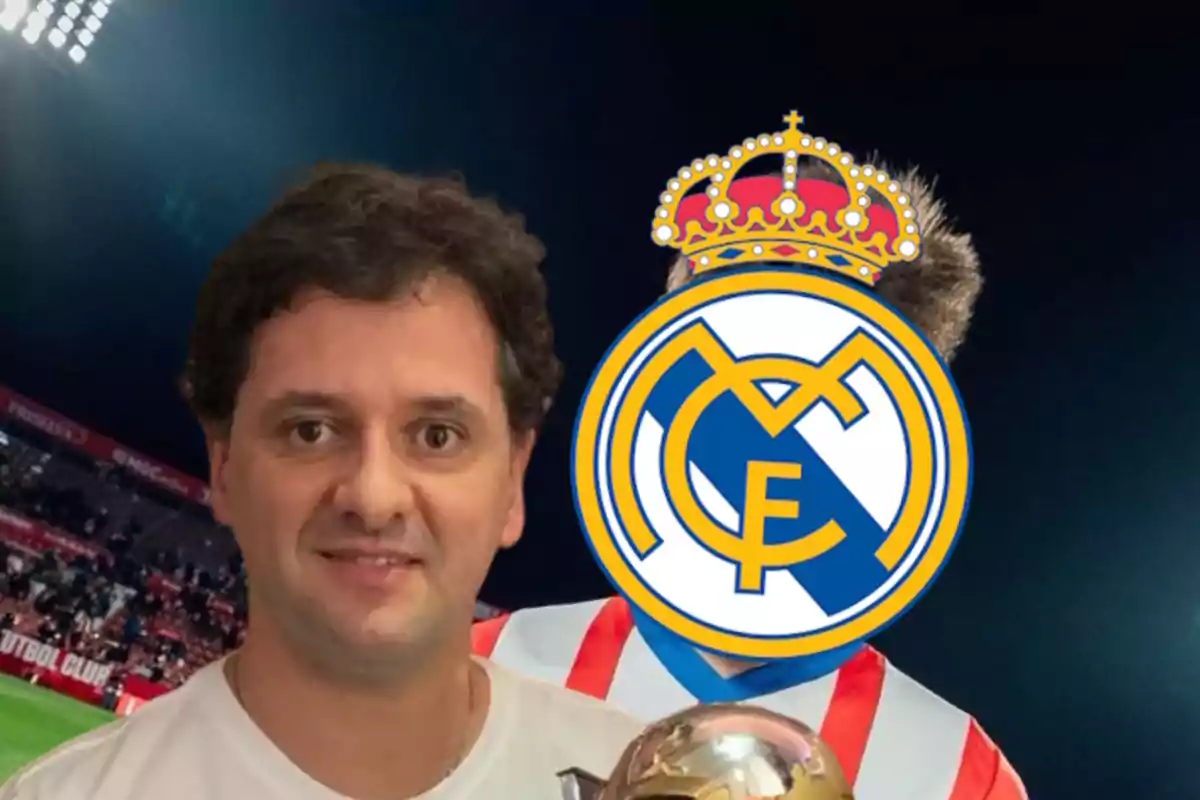 A smiling man holds a trophy while standing next to a person with their face covered by the Real Madrid crest in a soccer stadium.