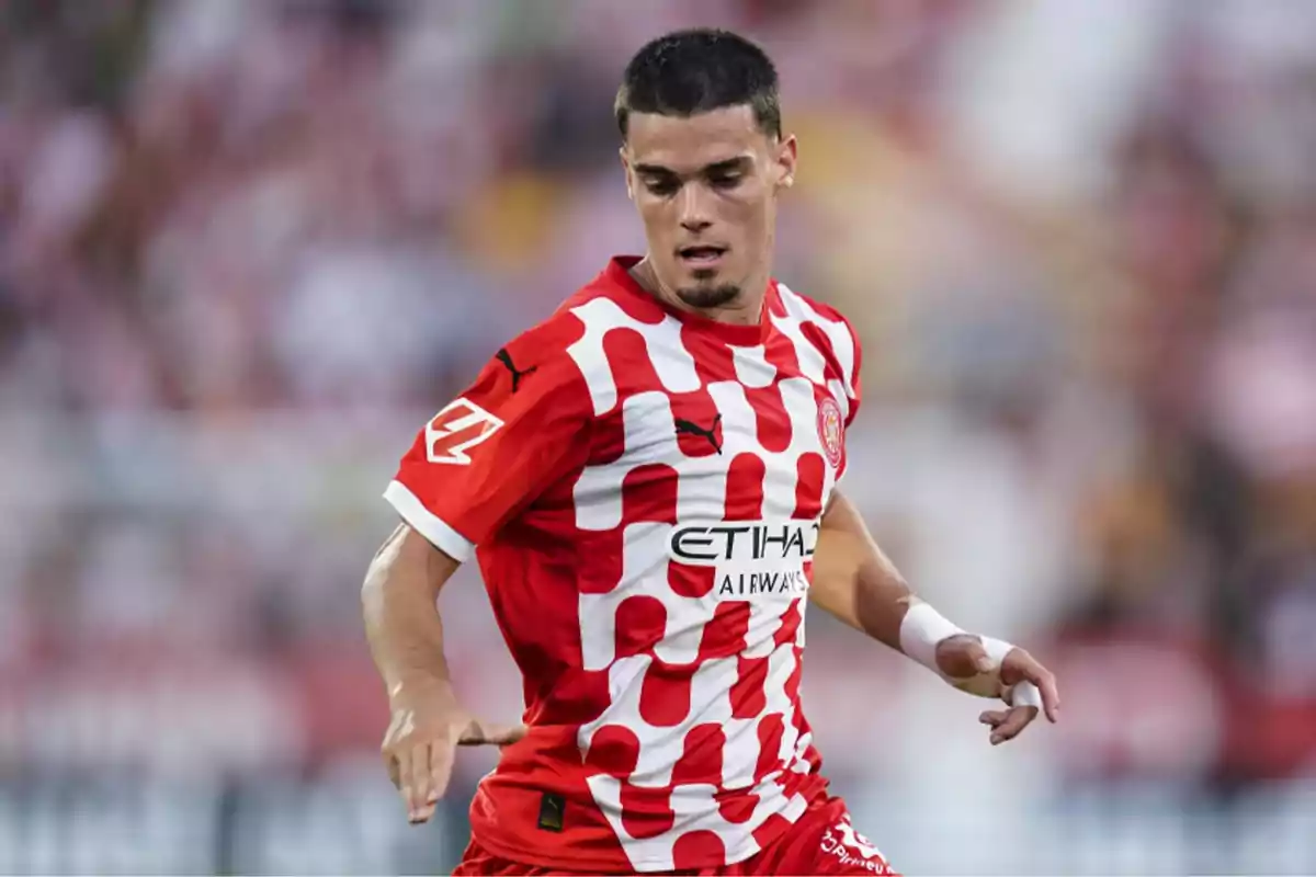 Jugador de fútbol con uniforme rojo y blanco en acción durante un partido.