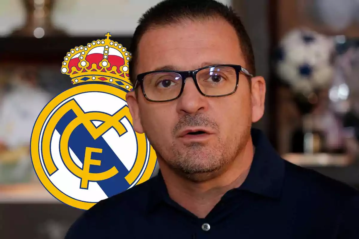 Un hombre con gafas y barba frente al escudo del Real Madrid.