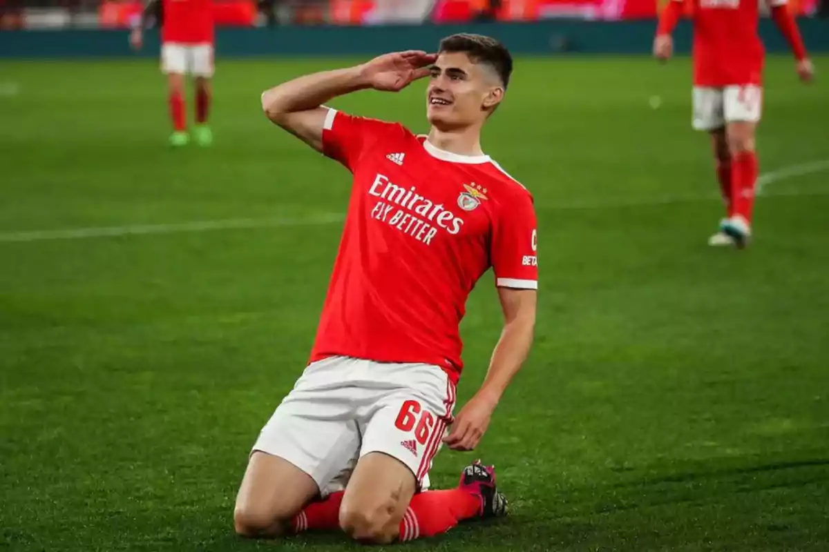 Football player in red uniform celebrating on the field while kneeling and gesturing with his hand on his forehead. Football player in red uniform celebrating on the field while kneeling and gesturing with his hand on his forehead.