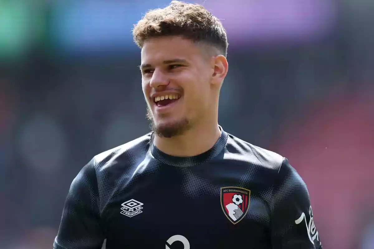 Smiling footballer wearing an AFC Bournemouth training jersey in a stadium Smiling footballer wearing an AFC Bournemouth training jersey in a stadium