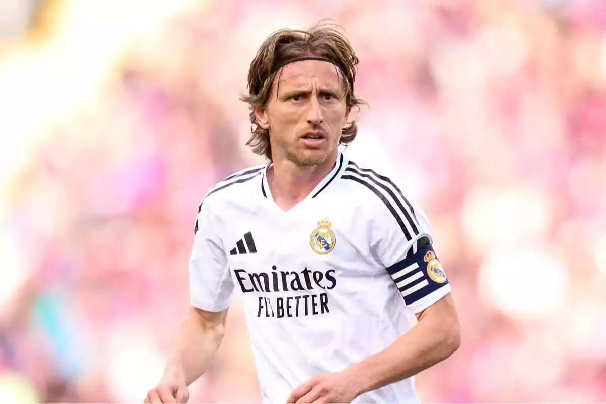 A player in a white uniform with a captain's armband during a match. A player in a white uniform with a captain's armband during a match.