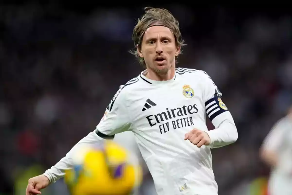 Jugador de fútbol con uniforme blanco del Real Madrid en acción durante un partido. Jugador de fútbol con uniforme blanco del Real Madrid en acción durante un partido.